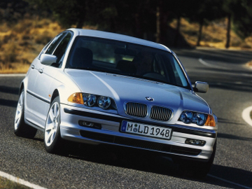 Front three-quarter view of a silver BMW sedan driving on a winding road.