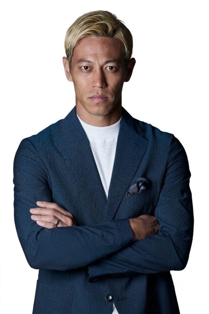 本田プロフィール写真 1 | 車買取のソコカラ Portrait of a man with blond hair in a navy blazer, white shirt, arms crossed