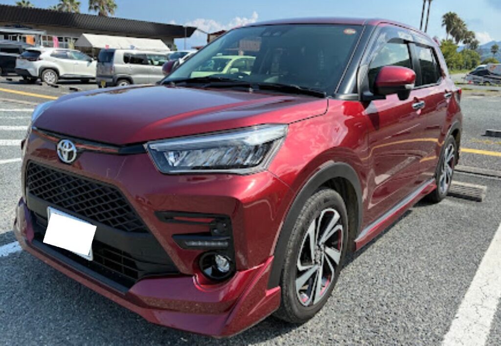 Red Toyota SUV parked in a lot, front-left angle, daytime with other cars in background.