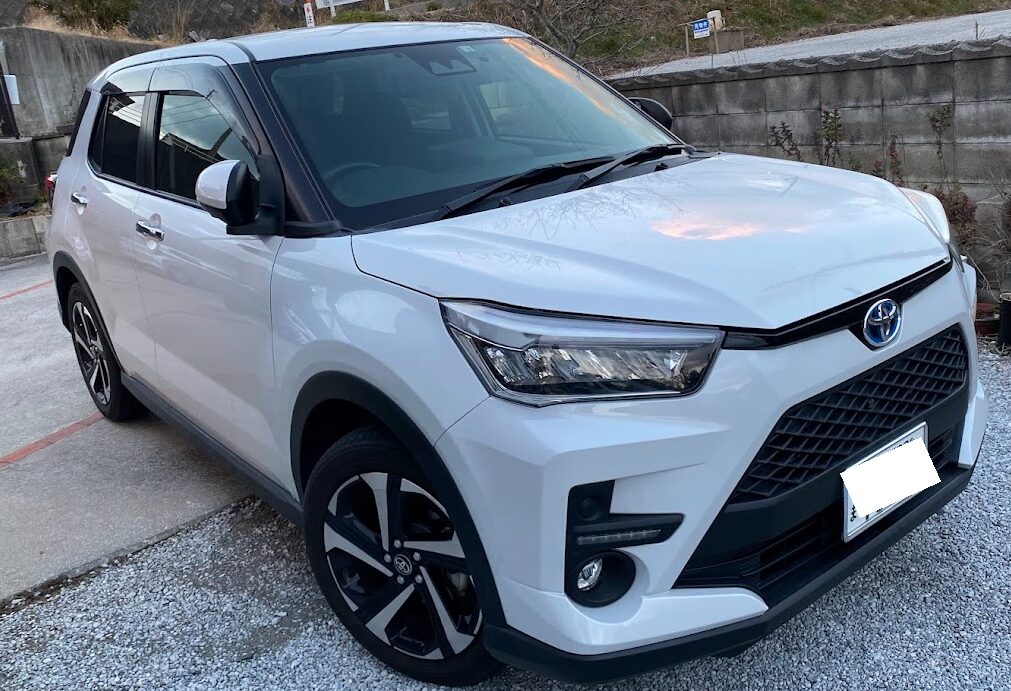 White Toyota SUV parked on gravel, front three-quarter view with black grille and angular headlights.",