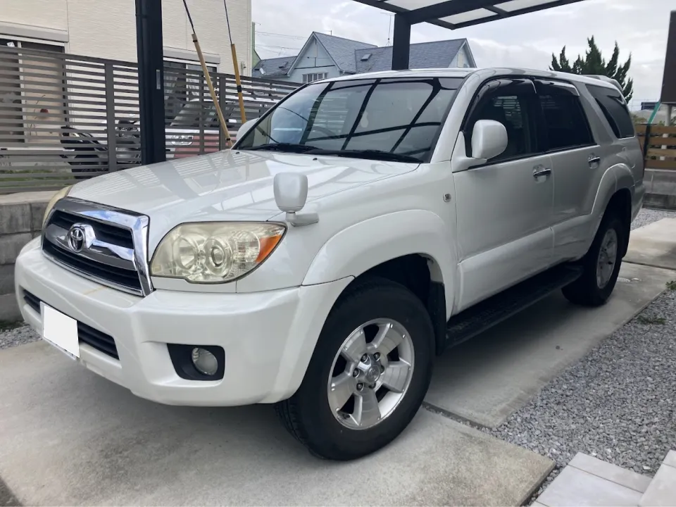 ハイラックス2008年式買取事例 | 車買取のソコカラ White Toyota SUV parked on a concrete driveway under a carport, shown from the front‑right three‑quarter view.