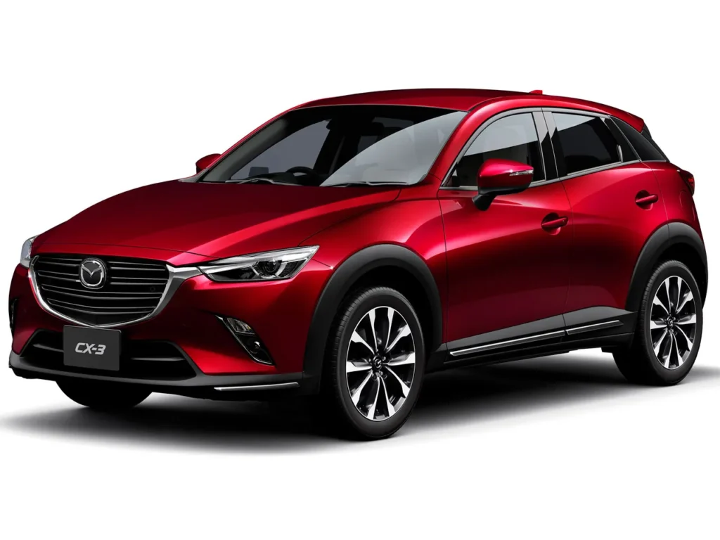 CX-3_2015_2 | 車買取のソコカラ Red Mazda CX-3 compact SUV shown in a three-quarter front view, highlighting its metallic finish and sleek design.”,